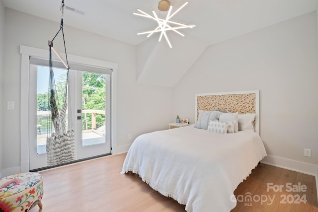 bedroom featuring access to exterior, hardwood / wood-style flooring, an inviting chandelier, and multiple windows