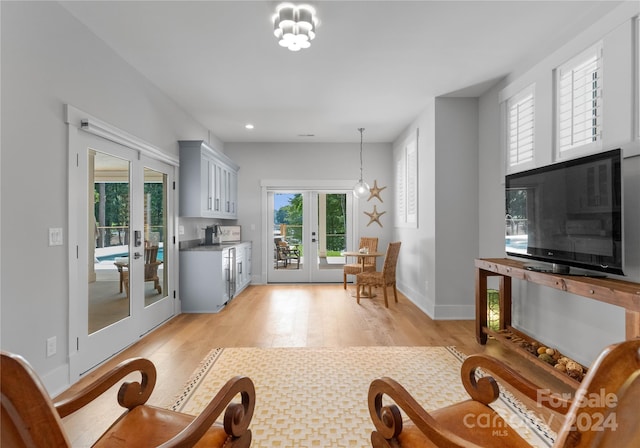 living room featuring a notable chandelier, light wood-type flooring, and french doors