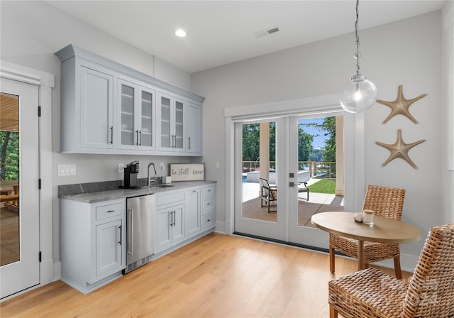 interior space featuring light stone countertops, french doors, light wood-type flooring, pendant lighting, and dishwasher