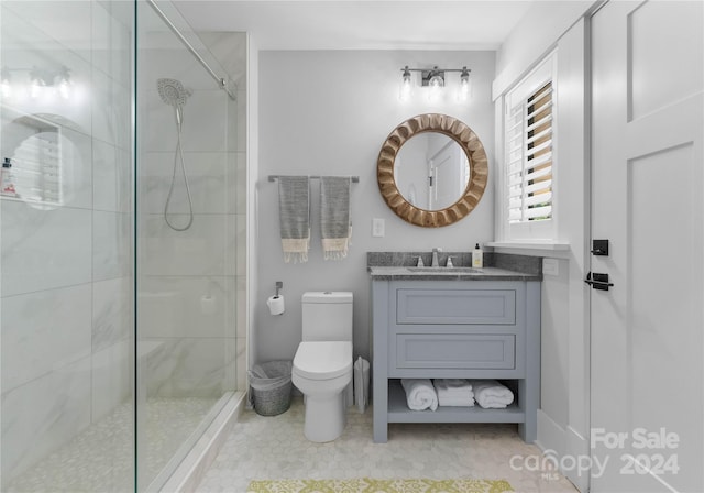 bathroom with a tile shower, tile patterned flooring, vanity, and toilet