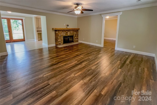 unfurnished living room with dark hardwood / wood-style flooring, a stone fireplace, ceiling fan, and crown molding