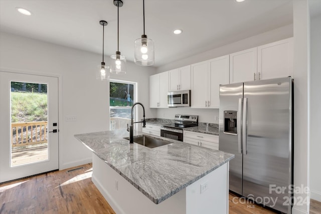 kitchen with sink, white cabinets, stainless steel appliances, and a center island with sink