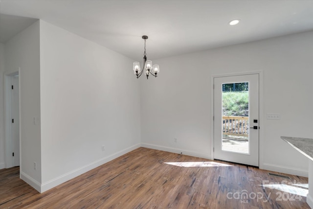 unfurnished dining area featuring wood-type flooring and a notable chandelier