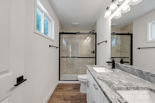 bathroom featuring hardwood / wood-style floors, vanity, a shower with shower door, and toilet