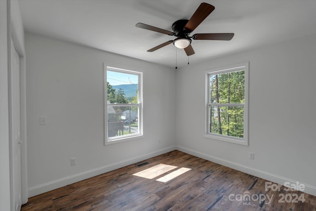 spare room with ceiling fan, a healthy amount of sunlight, and dark wood-type flooring