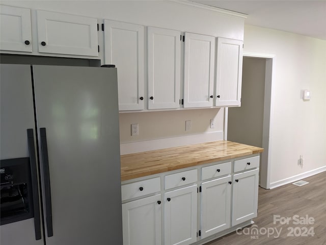 kitchen with stainless steel fridge with ice dispenser, white cabinetry, light hardwood / wood-style flooring, and butcher block countertops