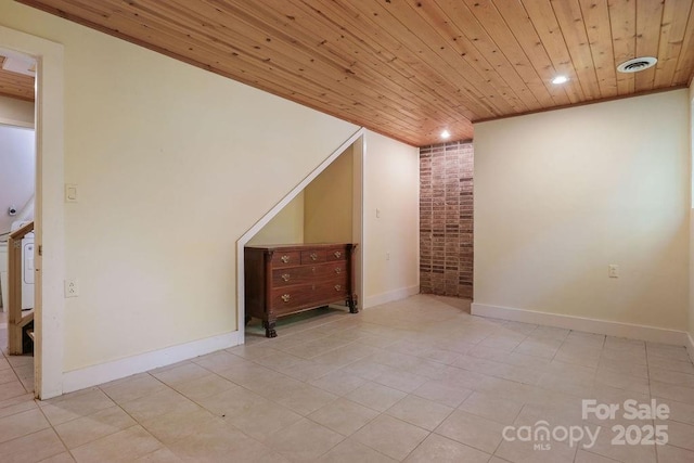 unfurnished room with light tile patterned floors, wood ceiling, and brick wall