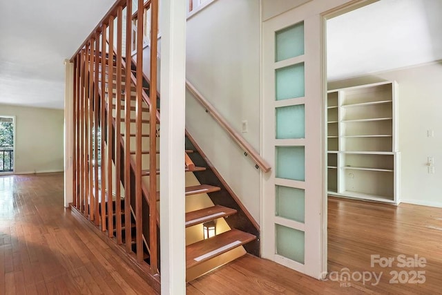 staircase featuring built in shelves and hardwood / wood-style floors