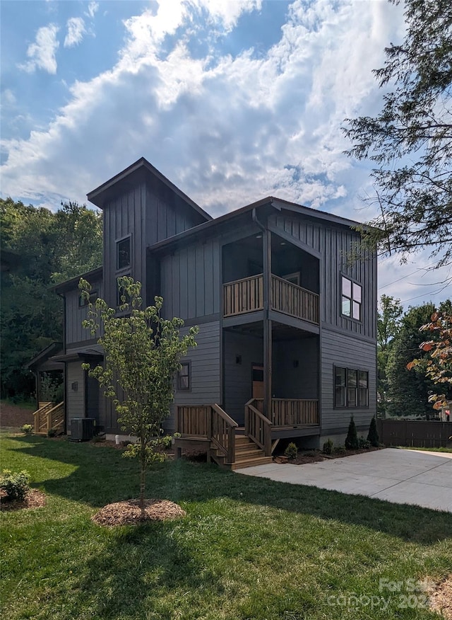 rear view of house featuring a balcony, central AC unit, and a lawn