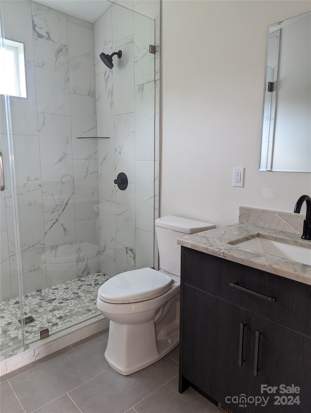 bathroom with tile patterned flooring, vanity, toilet, and an enclosed shower