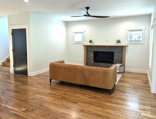 living room with ceiling fan, a tiled fireplace, and hardwood / wood-style floors