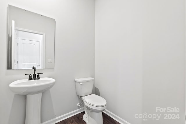 bathroom with hardwood / wood-style floors, toilet, and sink