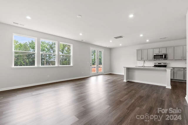 unfurnished living room with plenty of natural light, sink, and dark wood-type flooring