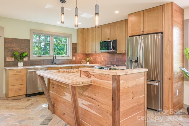 kitchen with decorative light fixtures, sink, appliances with stainless steel finishes, and tasteful backsplash