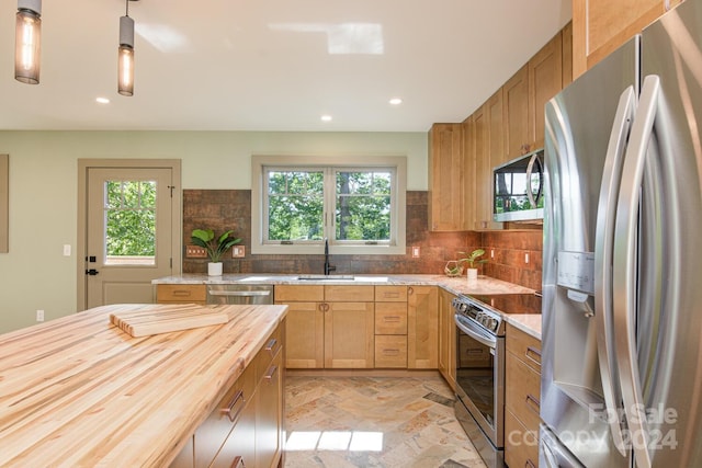 kitchen with wooden counters, appliances with stainless steel finishes, backsplash, sink, and decorative light fixtures