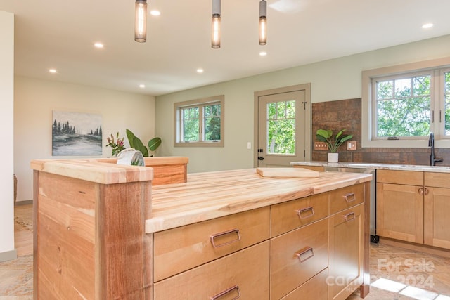 kitchen featuring a healthy amount of sunlight, a center island, wooden counters, and sink