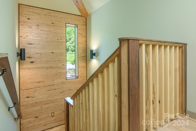 stairs with wood walls and lofted ceiling