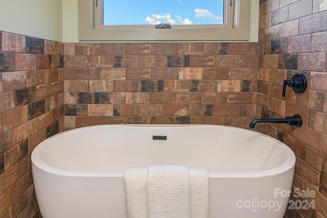 bathroom featuring a tub to relax in, a wealth of natural light, and tile walls