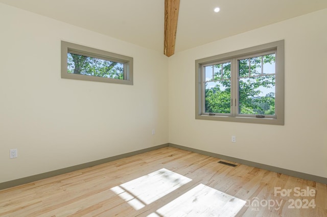 unfurnished room featuring beam ceiling and light wood-type flooring