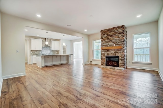 unfurnished living room featuring light wood-type flooring, a wealth of natural light, and a fireplace