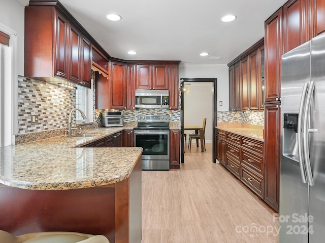 kitchen with stainless steel appliances, sink, kitchen peninsula, light hardwood / wood-style flooring, and a breakfast bar area