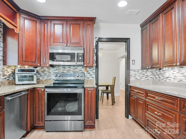 kitchen with light stone counters, appliances with stainless steel finishes, and crown molding