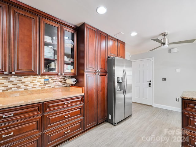 kitchen with tasteful backsplash, ceiling fan, stainless steel fridge, light stone counters, and light hardwood / wood-style flooring