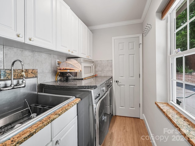 laundry room featuring sink, light hardwood / wood-style flooring, separate washer and dryer, ornamental molding, and cabinets