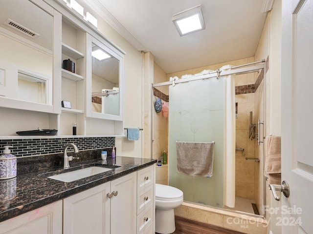 bathroom with toilet, a shower with shower door, tasteful backsplash, and vanity