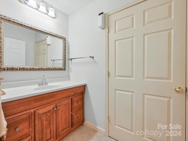 bathroom with a textured ceiling, tile patterned flooring, and vanity