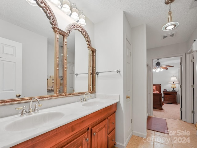 bathroom with a textured ceiling, ceiling fan, tile patterned flooring, and vanity