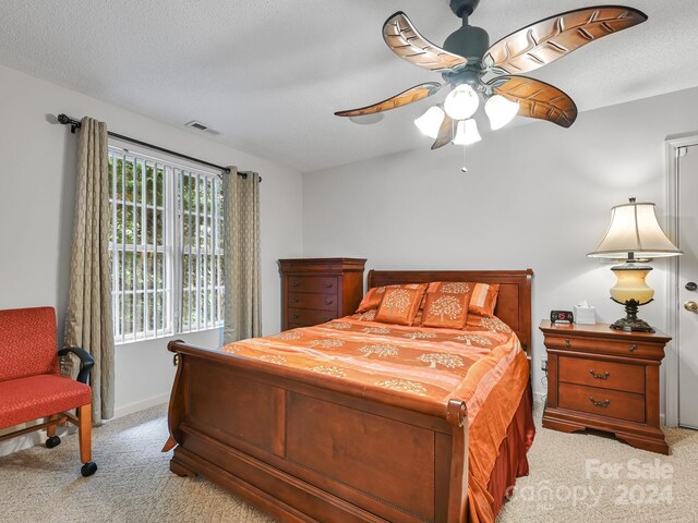 bedroom with a textured ceiling, ceiling fan, and light colored carpet