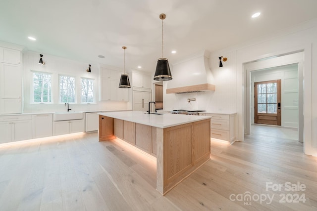 kitchen with premium range hood, a spacious island, sink, decorative light fixtures, and white cabinetry