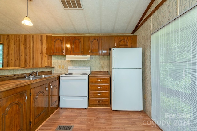 kitchen featuring sink, hanging light fixtures, light hardwood / wood-style floors, lofted ceiling, and white appliances