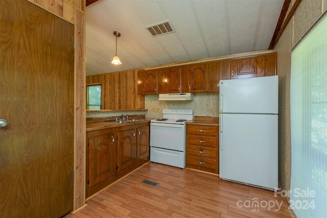 kitchen with pendant lighting, white appliances, light hardwood / wood-style floors, and sink