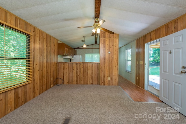 entryway featuring carpet flooring, wooden walls, ceiling fan, and lofted ceiling