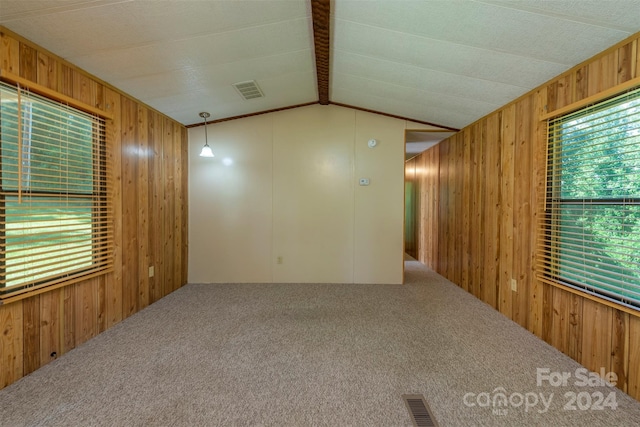 unfurnished room with vaulted ceiling with beams, wood walls, and carpet floors