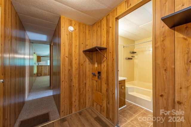 bathroom featuring shower / bathing tub combination, vanity, and wooden walls