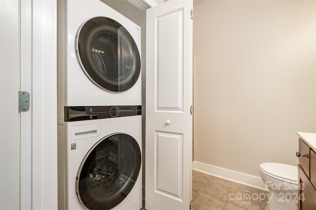 laundry room with stacked washer / drying machine and light tile patterned floors