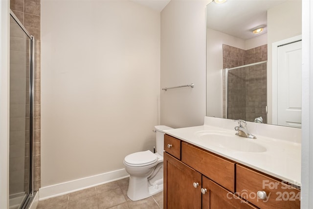 bathroom featuring tile patterned floors, a shower with door, vanity, and toilet