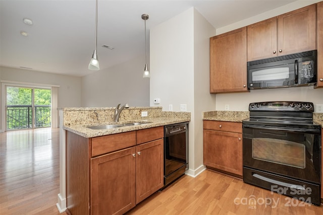 kitchen featuring sink, kitchen peninsula, pendant lighting, black appliances, and light wood-type flooring