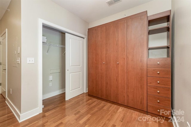 unfurnished bedroom with light wood-type flooring and a closet