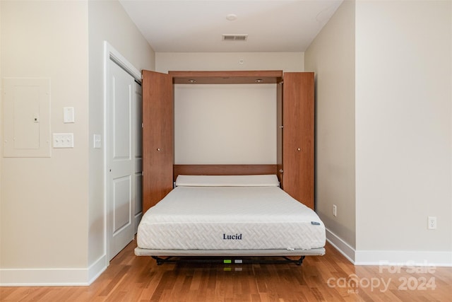 unfurnished bedroom featuring hardwood / wood-style floors, electric panel, and a closet