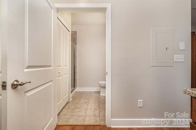 bathroom featuring tile patterned flooring, electric panel, toilet, and walk in shower