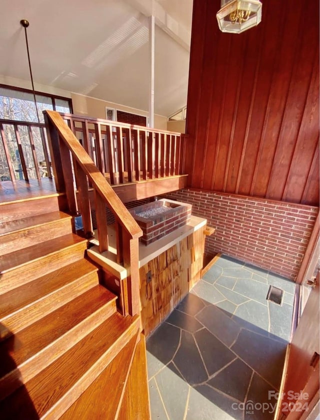 stairs featuring wooden walls and lofted ceiling