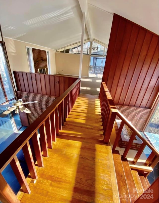 stairway with vaulted ceiling with beams, ceiling fan, and wood-type flooring