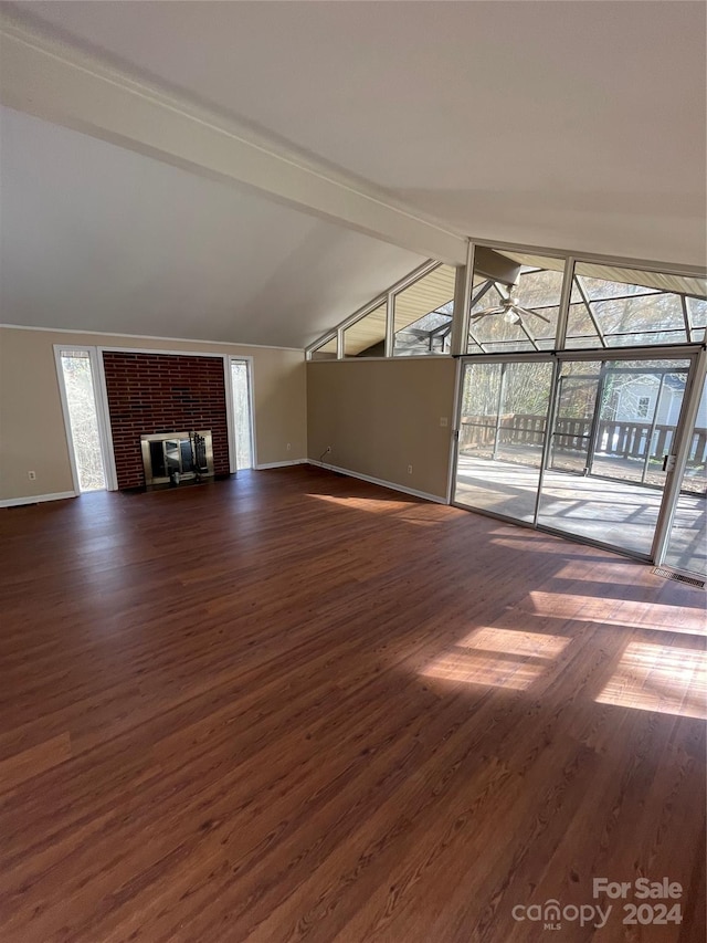 unfurnished living room featuring a healthy amount of sunlight, lofted ceiling with beams, a fireplace, and dark wood-type flooring