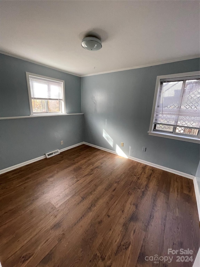 empty room featuring crown molding and dark hardwood / wood-style flooring