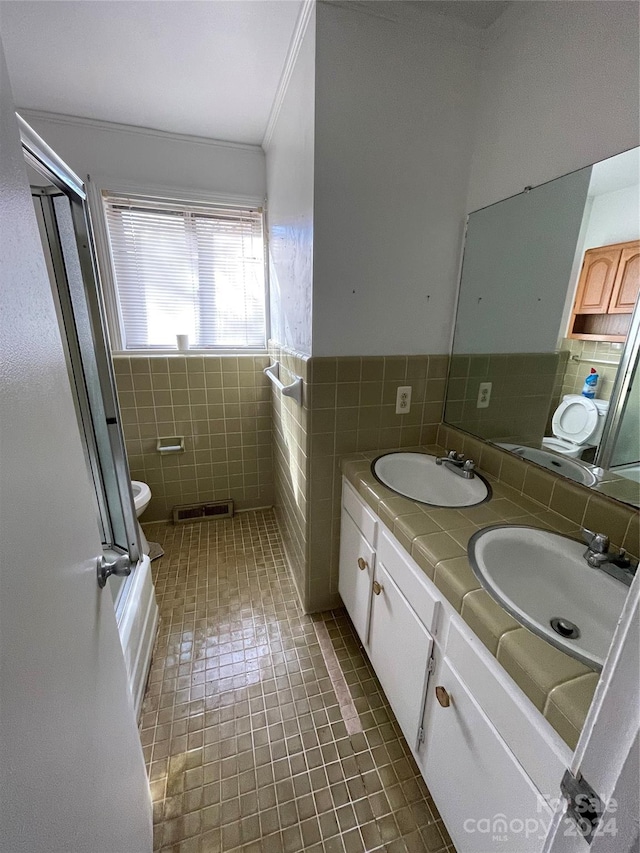 bathroom featuring tile patterned floors, vanity, crown molding, tile walls, and toilet