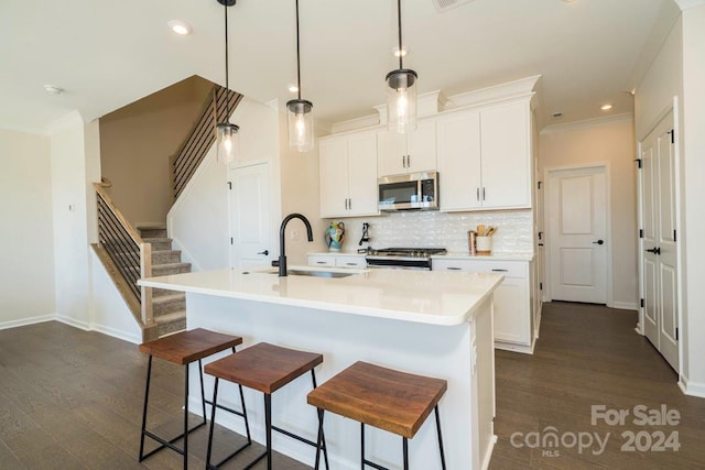 kitchen with dark wood-type flooring, an island with sink, and stainless steel appliances